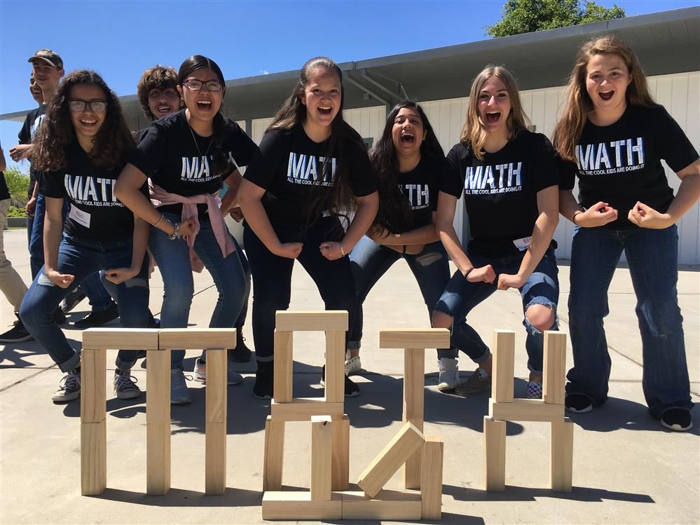 Five girls jumping behind the word Math made of blocks